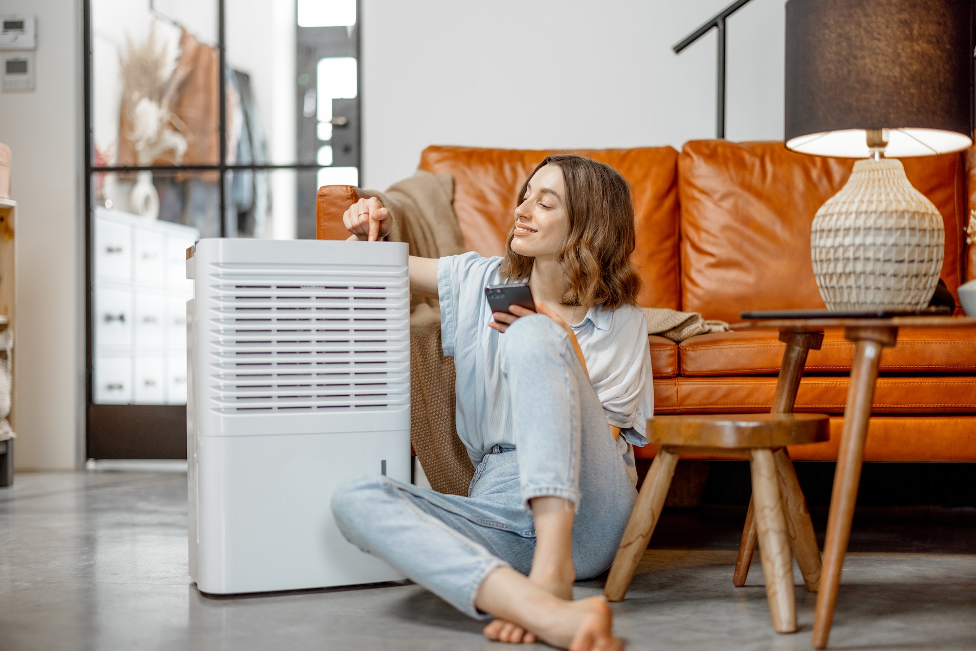 Woman sitting near air purifier and moisturizer appliance